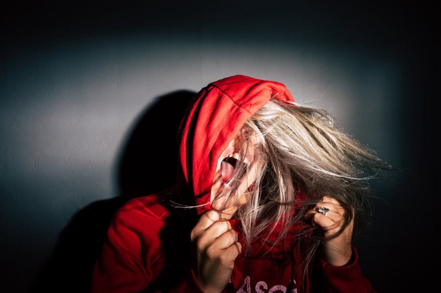 A woman in a red hoodie sweatshirt screaming in frustration